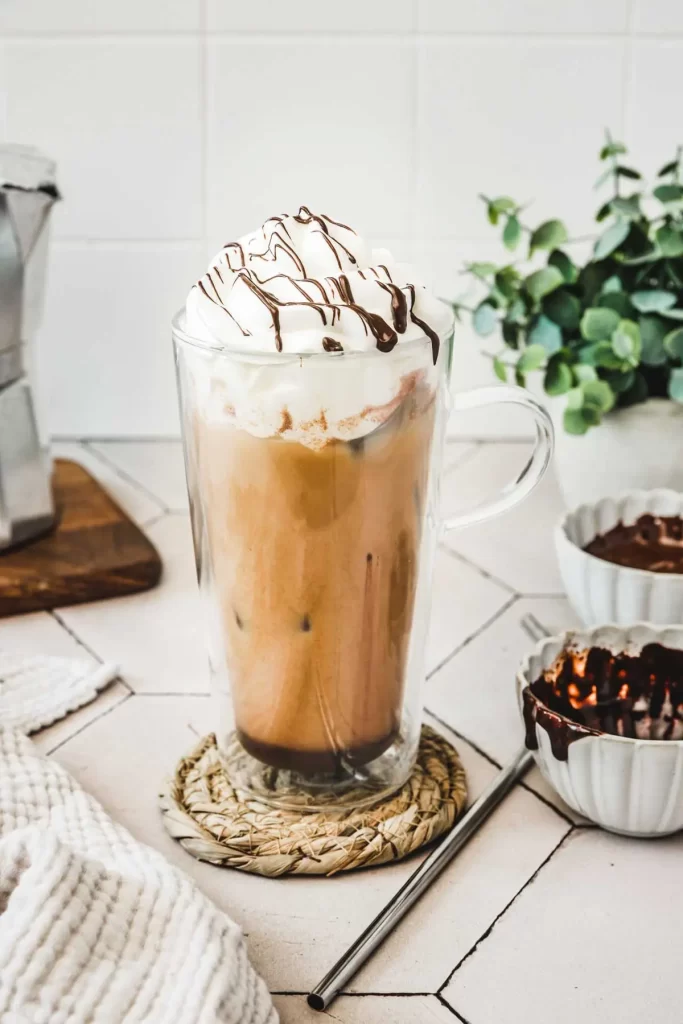 big mug of mocha iced latte with whipped cream placed on a counter