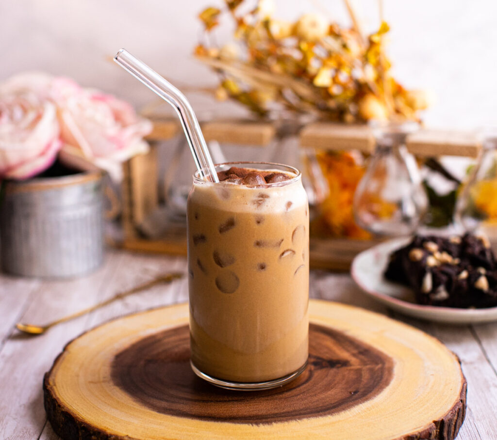 glass of iced peanut butter coffee with a straw on a tray