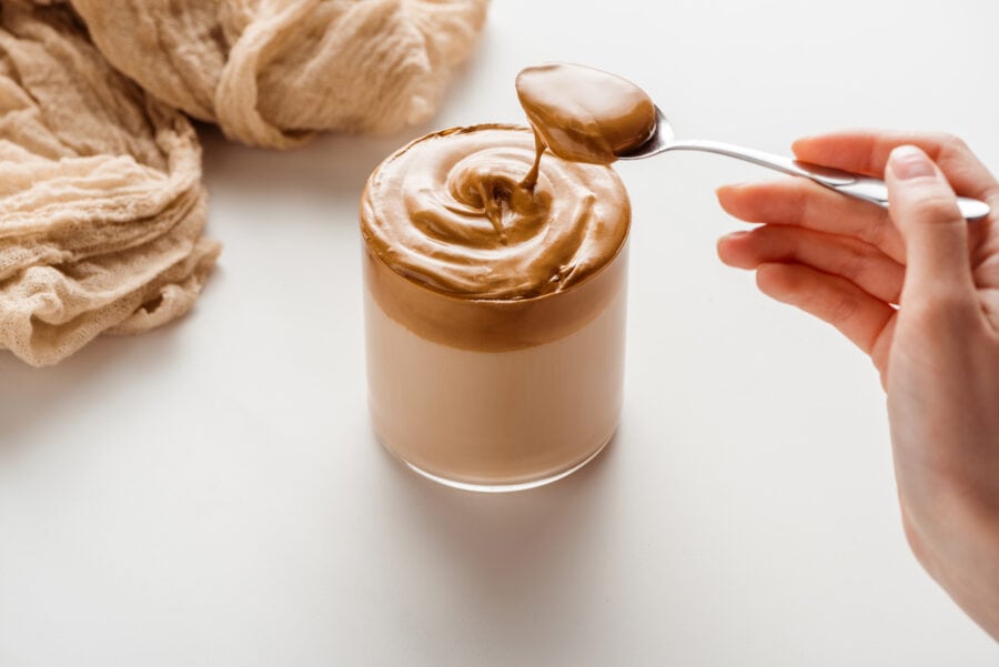 someone pouring peanutg butter in a glass of coffee