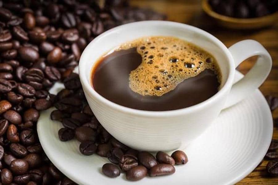 Luwak coffee in a cup with coffee beans spilled around