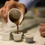 a person puring colada coffee in mini cups