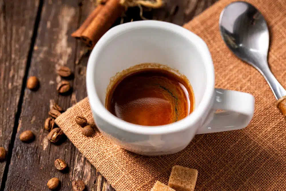 brewed ristretto shot in a cup a spoon and some coffee beans