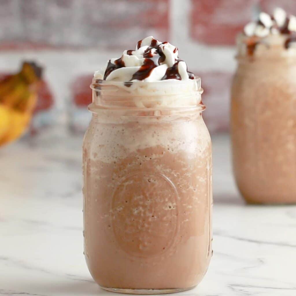 peanut butter banana smoothie in a jar with whipped cream on top