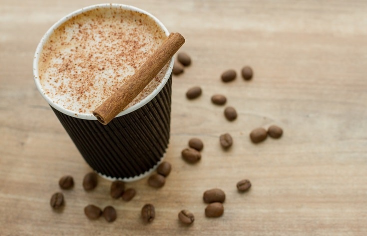 toppings for coffee cinnamon stick cocoa pwder sprinkled on the cup of coffee some coffee beans on the surface