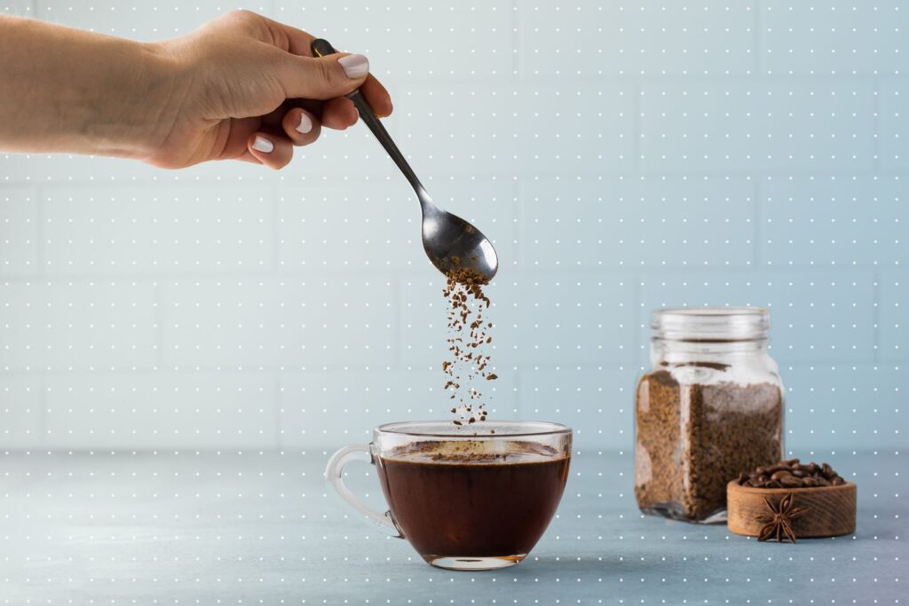 female hand carrying spon and mixing coffeee beans in a cup of coffee