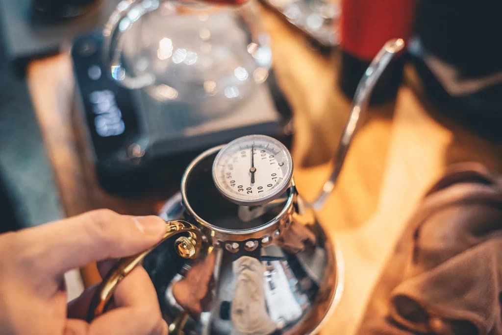 a male hand holding thermometer to measure coffee temperature