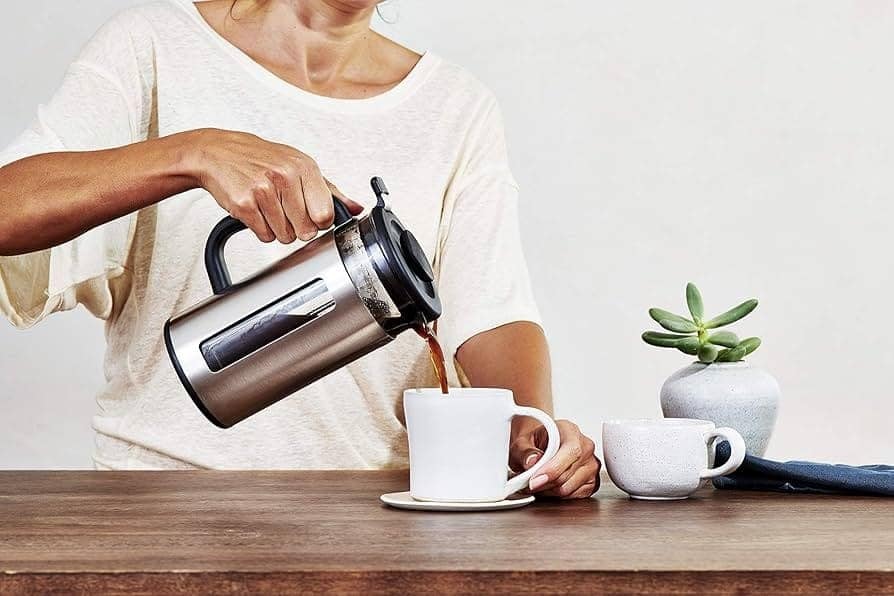 close up of a female half body pouring coffee in a cup