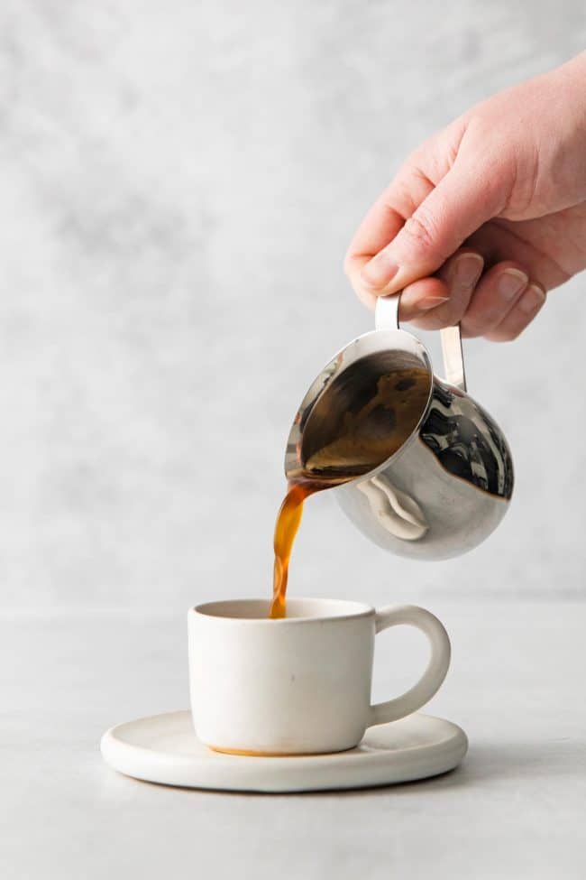 zoomed in view of a hand pouring coffee in cup