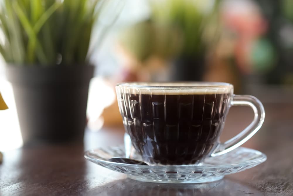 Americano Coffee On Wooden Table And Sunlight Background