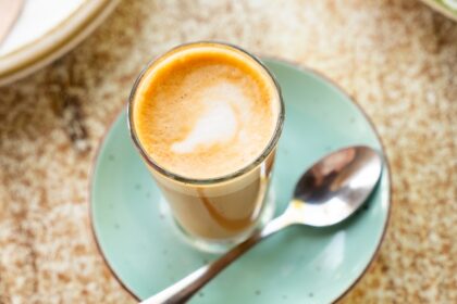 cortado drink in a cup placed on a plate with a spoon