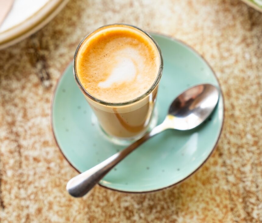 cortado drink in a cup placed on a plate with a spoon