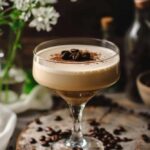 a glass of coffee cocktail on a round wooden serving platform garnished with coffee beans