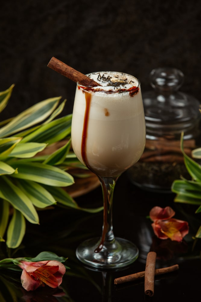 a glass of white russian coffee cocktail with creamy froth and cinamon roll as garnish