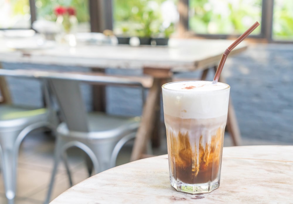 a glass of creamy Irish coffee cocktail with a straw inside