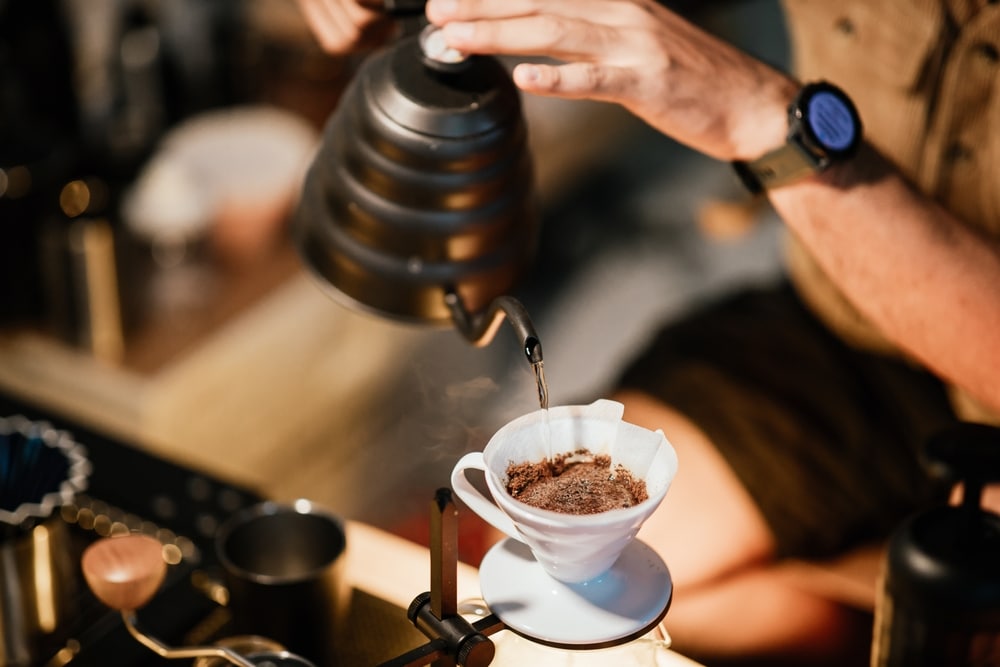 Barista Making Drip Coffee With Hot Water Being Poured From kettle