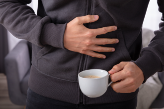 Man Suffering From Stomach Pain With Cup Of Coffee