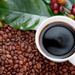 Raw or ripe red branch of Arabica and Robusta and organic coffee berries beans and a cup of coffee