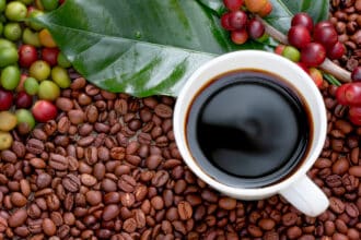 Raw or ripe red branch of Arabica and Robusta and organic coffee berries beans and a cup of coffee