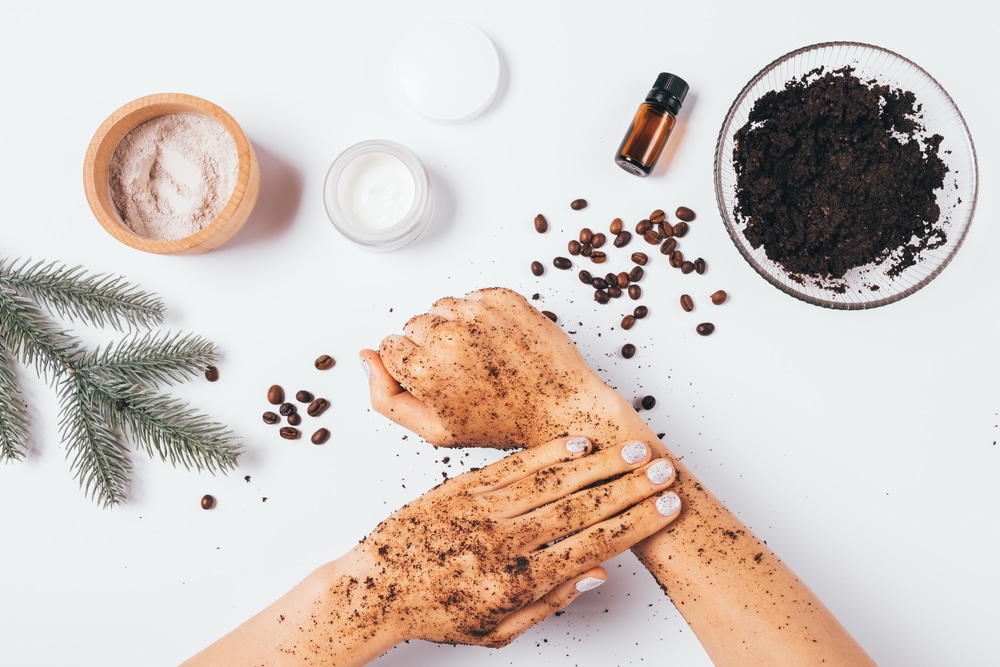 female hands making peeling procedure with homemade cosmetic coffee scrub with clay and pine essential oil